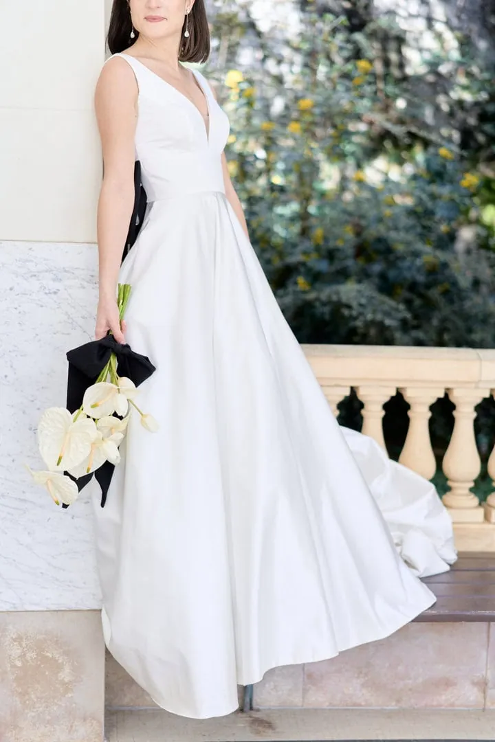 Mariée en robe blanche tenant un bouquet d'arums sur une terrasse