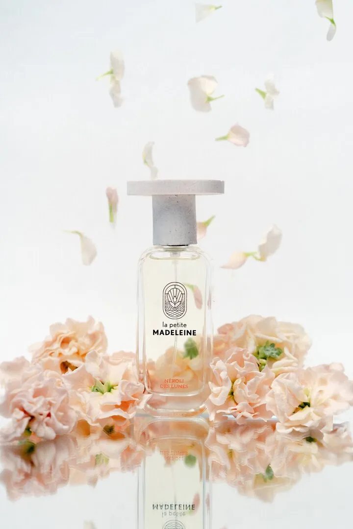 Parfum sur un miroir, fond neutre et pétales de fleurs en suspension