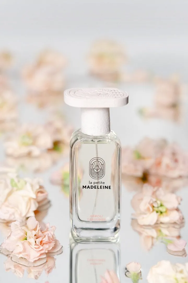 Flacon de parfum sur un miroir, fleurs roses en arrière-plan
