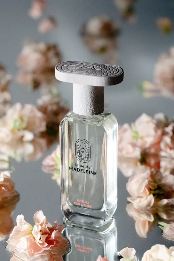 Parfum mis en scène sur un miroir avec des fleurs