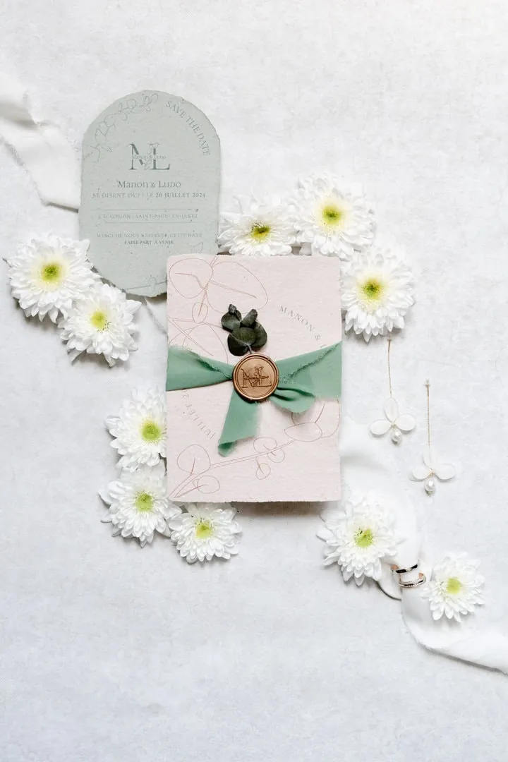 Faire-part fermé par un ruban vert et un sceau de cire, entouré de marguerites